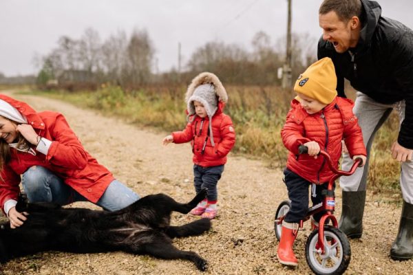 Happy family enjoying quality time outdoors with kids and dog in countryside.